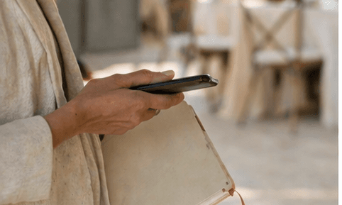 A planner holding a phone over an open notebook, a venue setting beyond